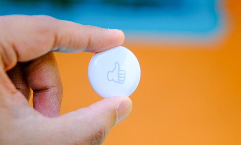 A white Apple AirTag Bluetooth tracker with a 