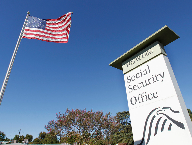FILE PHOTO: An American flag flutters in the wind next to signage for a United States Social Security Administration office in Burbank, California October 25, 2012. REUTERS/Fred Prouser/File Photo