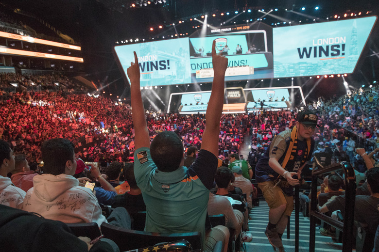 FILE - In this July 28, 2018, file photo, London Spitfire fan Rick Ybarra, of Plainfield, Ind., reacts after London won the second game against the Philadelphia Fusion during the Overwatch League Grand Finals competition at Barclays Center in New York. Each Overwatch League franchise will host two to five homestand weekends in 2020 as the esports league launches an unprecedented home-and-away schedule spanning three continents. The esport league revealed Tuesday, July 16, 2019, plans for each of its 20 teams to host homestand series, similar to events staged by teams this year in Dallas, Atlanta and Los Angeles, as part of its 2020 regular season.(AP Photo/Mary Altaffer, File)