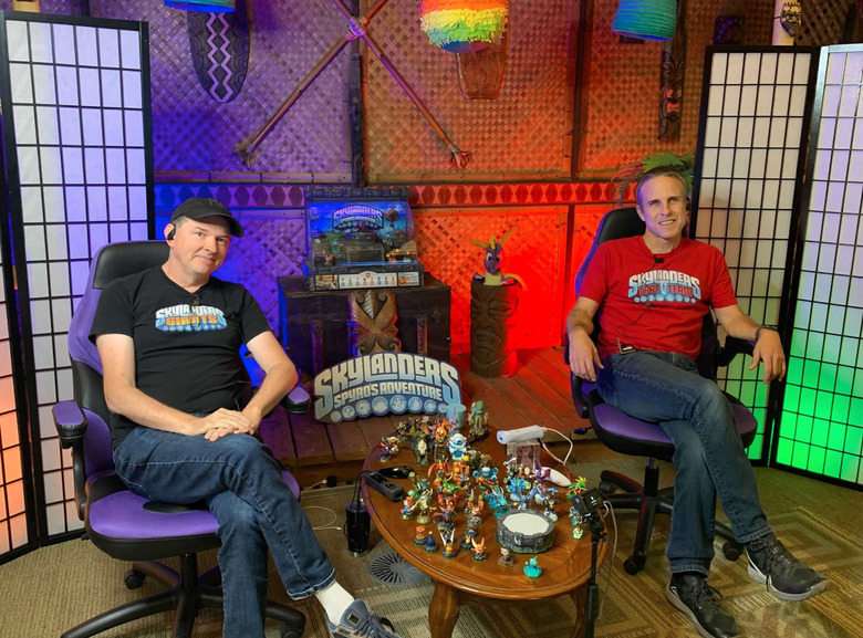 Two employees sitting in chairs surrounded by merch.