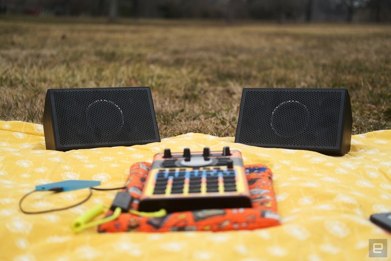 AIAIAI Unit 4 Wireless+ studio monitors on a picnic blanket in a park along with an SP-404 MKII with an adorable Speak & Spell skin. 