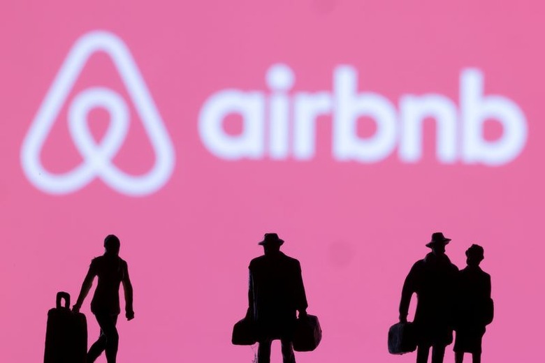 Figurines are seen in front of displayed Airbnb logo