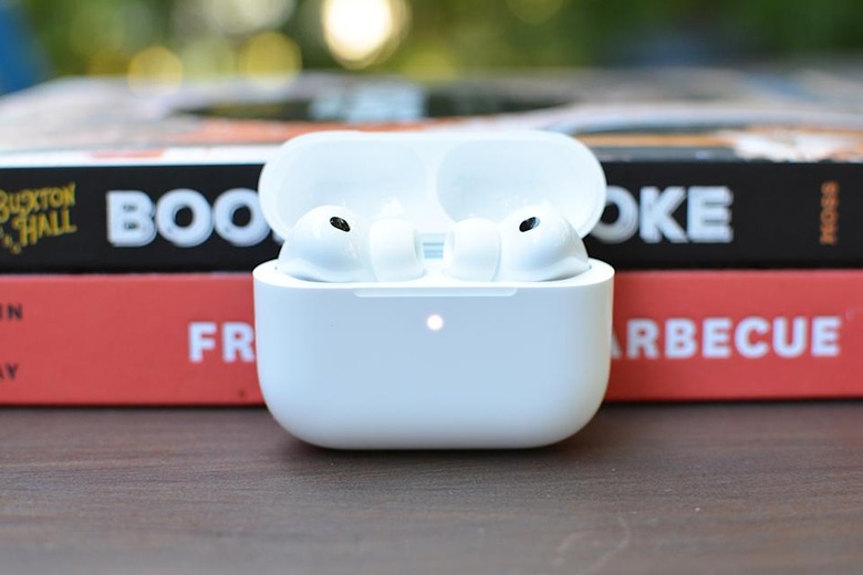 The AirPods Pro 3 pictured inside a case with the top open, propped up against two books