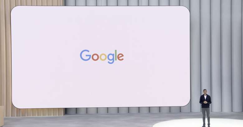Sundar Pichai standing in front of the Google logo at Google I/O 2025.