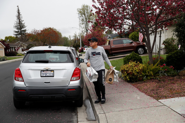 Excelso Sabulau, a 35-year-old independent contract delivery driver for Amazon Flex, carries deliveries to a house, as spread of the coronavirus disease (COVID-19) continues, in Dublin, California, U.S., April 6, 2020. Picture taken April 6, 2020. REUTERS/Shannon Stapleton