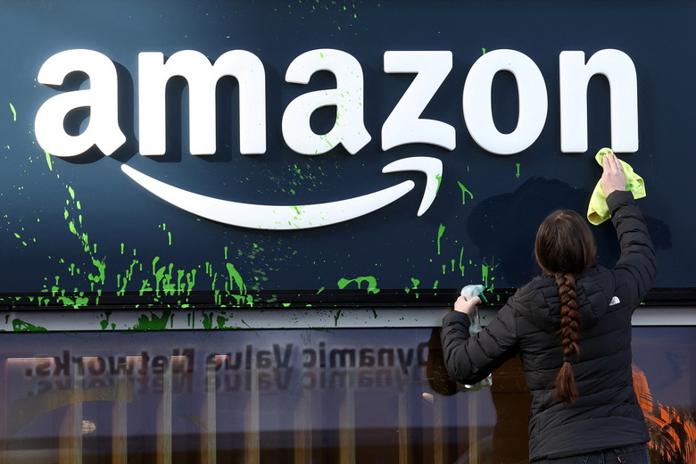 A woman cleans the storewindow of the Amazon house after activists sprayed paint its facade during a protest on the opening day of the 55th annual meeting of the World Economic Forum (WEF) in Davos, Switzerland, January 20, 2025. REUTERS/Yves Herman