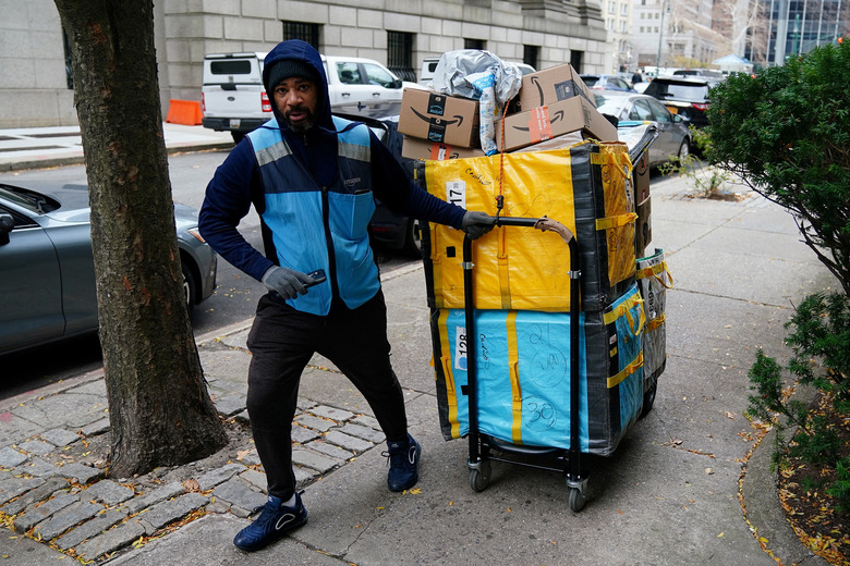 FILE PHOTO: An Amazon delivery person pulls a cart full of packages in the Manhattan borough of New York City, New York, U.S., December 10, 2021.  REUTERS/Carlo Allegri/File Photo