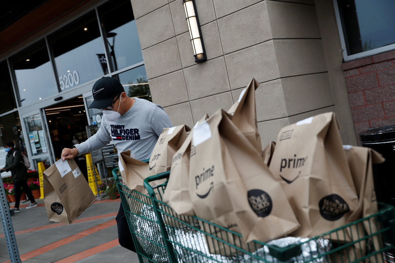 Excelso Sabulau, a 35-year-old independent contract delivery driver for Amazon Flex, wears a protective mask as he carries deliveries to his car near a Whole Foods Market, as spread of the coronavirus disease (COVID-19) continues, in Dublin, California, U.S., April 6, 2020. Picture taken April 6, 2020. REUTERS/Shannon Stapleton