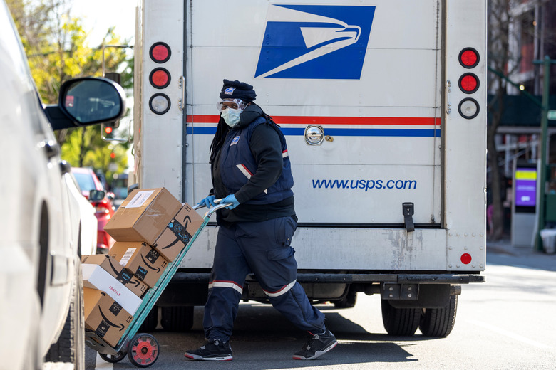 NEW YORK, NEW YORK - APRIL 28: A U.S.P.S. worker wearing a protective mask, gloves and safety goggles delivers mostly Amazon packages amid the coronavirus pandemic on April 28, 2020 in New York City. COVID-19 has spread to most countries around the world, claiming over 217,000 lives with over 3.1 million cases.  (Photo by Alexi Rosenfeld/Getty Images)