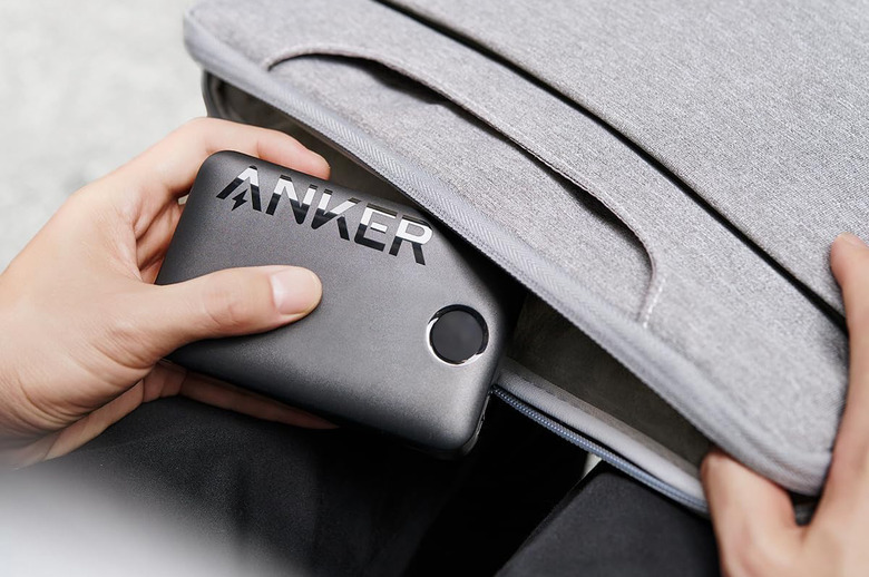 A black Anker-branded portable battery being inserted into a  bag.