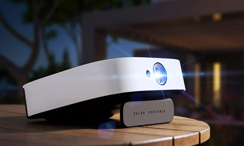 Anker Nebula Solar HD projector is set up outside on a round patio table made from wooden slats. The kickstand is propping up the projector.  