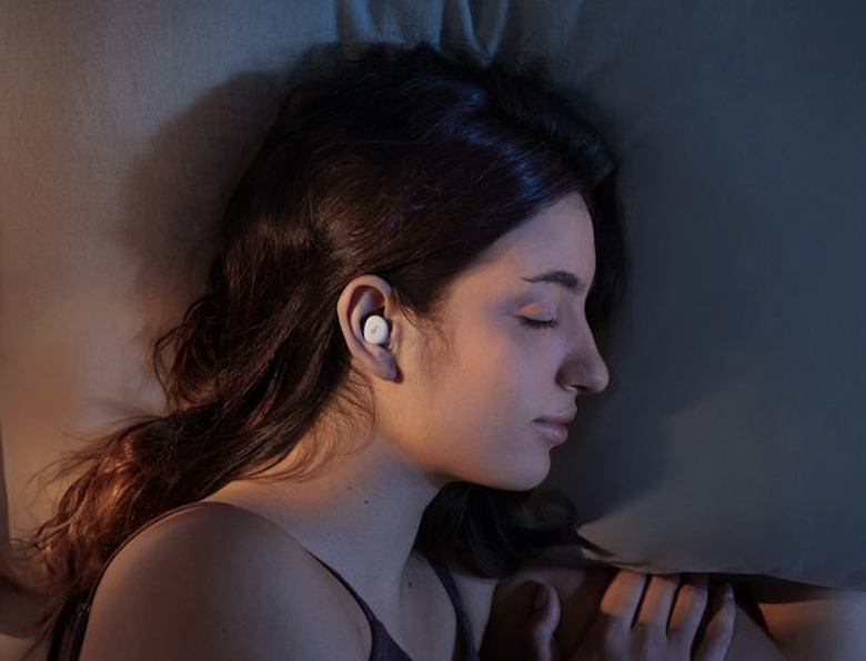 A lady sleeping with earbuds.