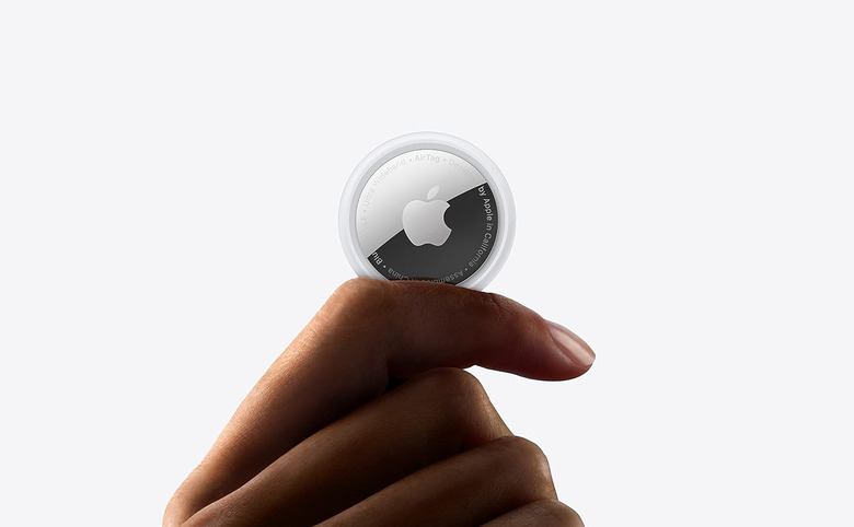 A hand holding a round, coin-sized device with the Apple logo.