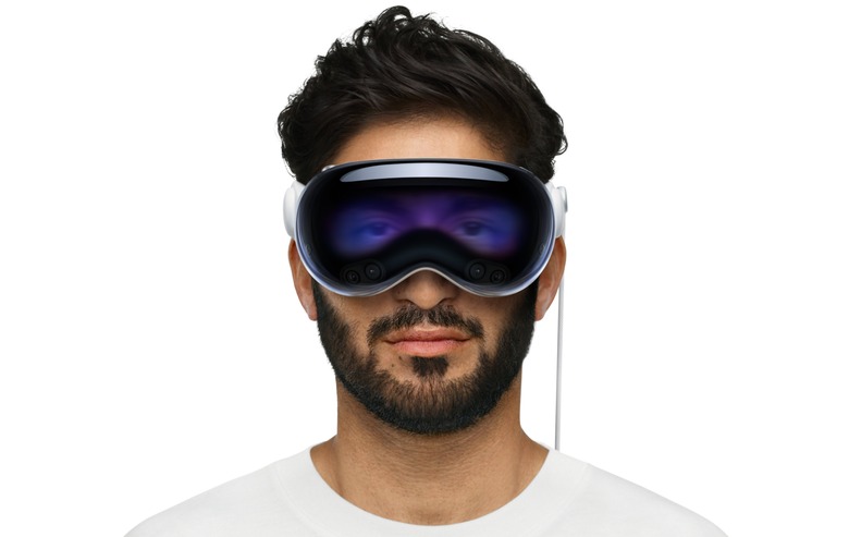 A man with dark brown hair and a beard is pictured straight-on wearing the Apple Vision Pro headset