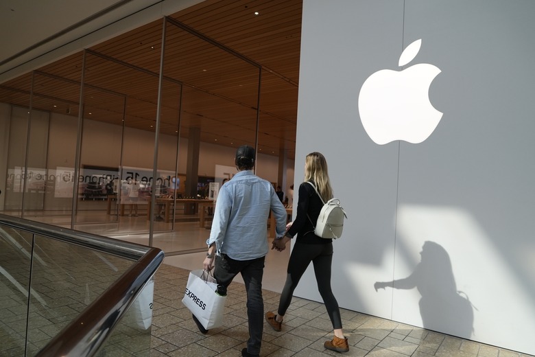People walk by an Apple store Oct. 20, 2023, in Denver. Apple is now requiring that U.S. law enforcement agencies obtain a court order for information on its customers' push notifications â?? the alerts iPhone apps send users that can reveal a lot about their online activity. (AP Photo/Brittany Peterson, File)