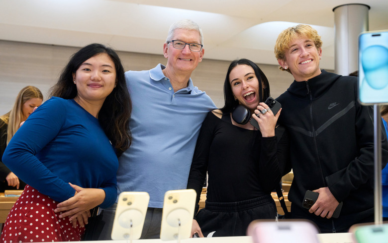 Four people posing behind a table with iPhone displays.