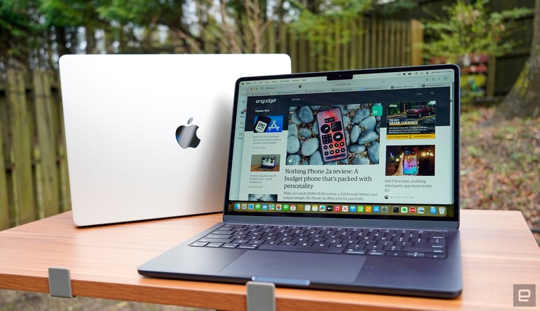 Photo of two Apple MacBook Airs, sitting one in front of the other on an outdoor table or desk.
