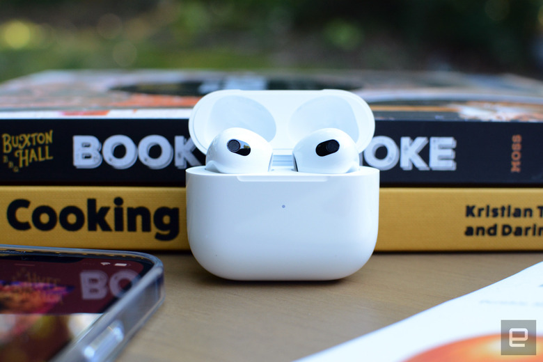 A photo of the third-gen Apple AirPods with black and yellow books in the background.