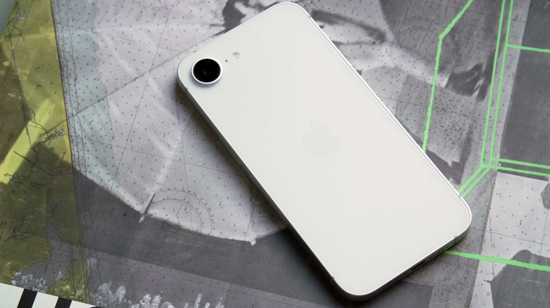 The iPhone 16e laying on a surface with its back facing up. A single camera sensor sits on the top left corner of the device. 