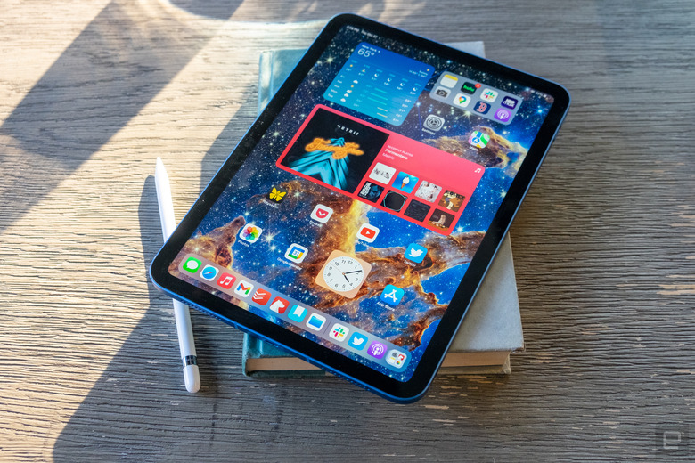 An Apple iPad on top of a book on a wooden table.