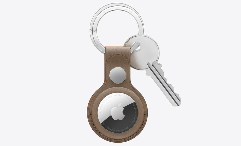 An Apple AirTag in a brown keyring caase with a silver key attached