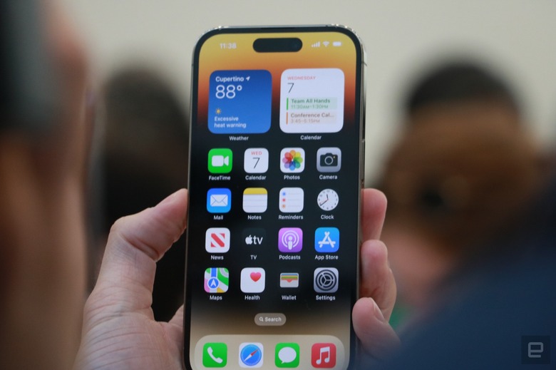 The iPhone 14 Pro held in mid-air, showing the new dynamic island at the top of the iOS home page.