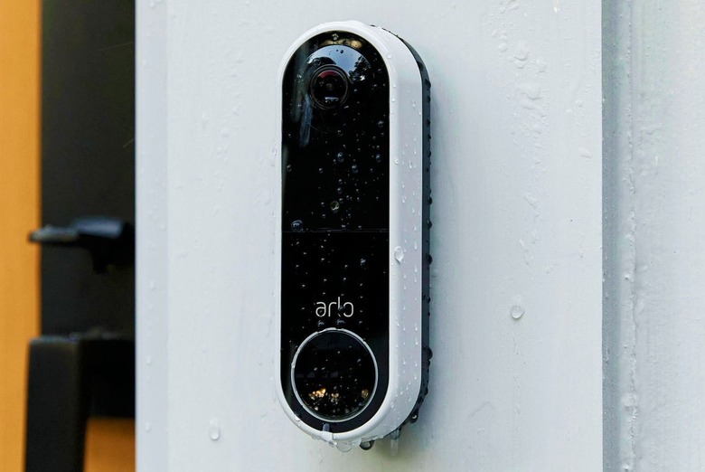Arlo's wireless video doorbell, fixed to a surface and covered in raindrops.