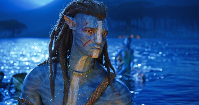 A closeup of Jake Sully in 20th Century Studios' AVATAR: THE WAY OF WATER with a large lake in the background.
