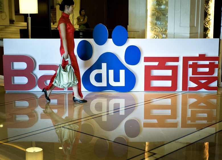 FILE - In this July 28, 2009 file photo a Chinese usher walks past the logo of Baidu Inc. on display during an event in Beijing. A possible Google pullout from China could give a boost to its ambitious local rival Baidu Inc., which dominates the Chinese market and is expanding abroad. (AP Photo/Andy Wong, File)