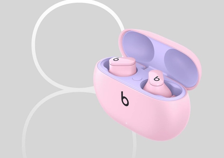 A pink pair of Beats Studio Buds against a gray and white background. 