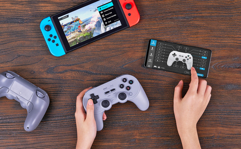 The 8BitDo wireless controller flanked by a Switch, a smartphone with controller setup graphics and two hands working the device.