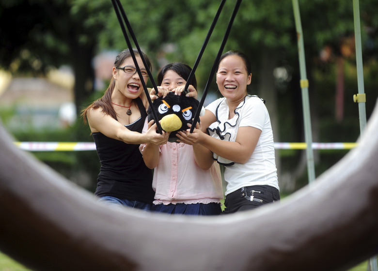 Visitors use a slingshot to shoot an Angry Bird plush toy at a real life Angry Birds outdoor game in a theme park at Changsha, Hunan province September 1, 2011. The game station, stimulating the popular smartphone video game, is part of a group of stress-reducing activities at Changsha's Colorful World theme park made available to the public from September 1-30. The theme park may be prosecuted for launching the game without permission from Finland-based Rovio, the original creators of Angry Birds, local media reported. Picture taken September 1, 2011. REUTERS/China Daily (CHINA - Tags: SOCIETY ENTERTAINMENT) CHINA OUT. NO COMMERCIAL OR EDITORIAL SALES IN CHINA