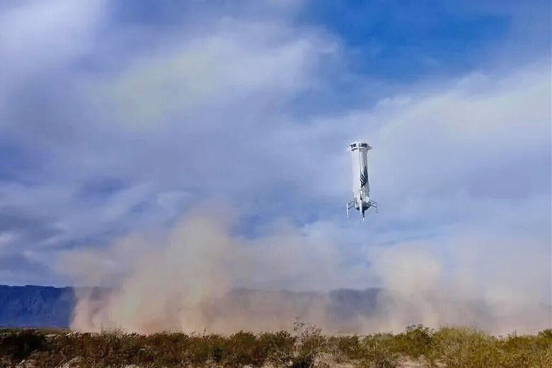 An image of a the Blue Origin New Shepard booster rocket lowering to Earth.  