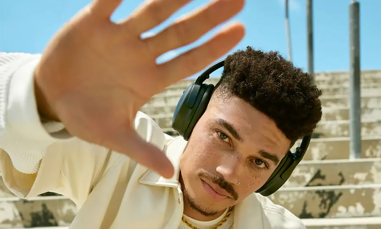 A person wearing the Bose QuietComfort headphones, holding their hand up to the camera. Outdoor stairs visible behind.