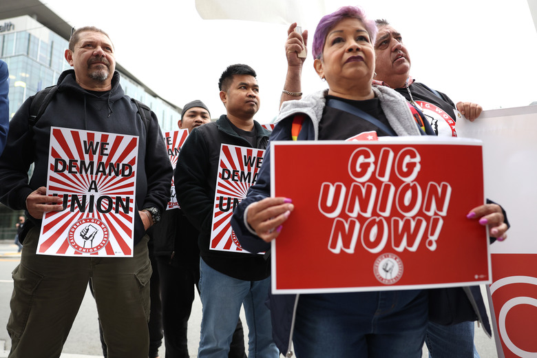 SAN FRANCISCO, CALIFORNIA - OCTOBER 12: Delivery drivers and gig workers hold signs as they protest in front of Uber headquarters on October 12, 2022 in San Francisco, California. Dozens of gig workers and delivery drivers staged a protest outside of Uber headquarters to announce the formation of the California Gig Workers Union after they say working conditions haven't improved since California voters passed Proposition 22 to classify  gig workers as independent contractors. Proposition 22 was later found to be unconstitutional under the California state constitution in August 2021 by a Superior Court judge. (Photo by Justin Sullivan/Getty Images)