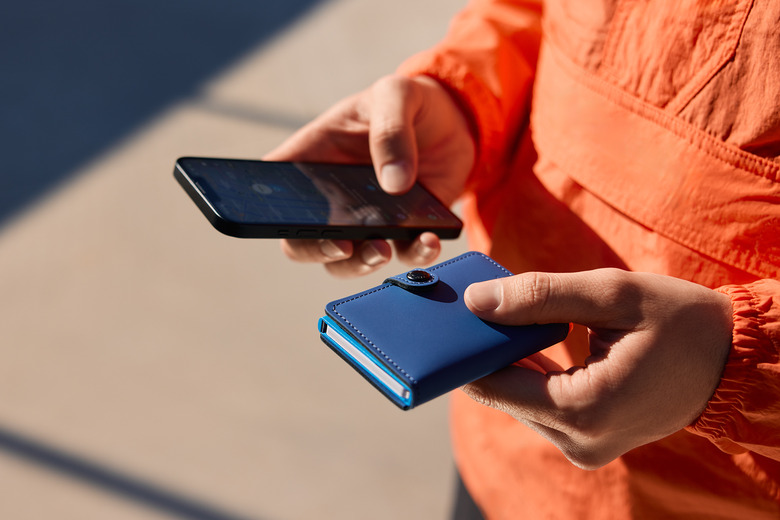 Image of a person holding their device and the new Chipolo x Sekrid wallet.