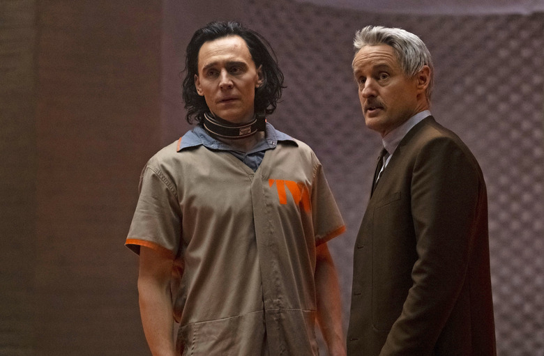 Media image from Disney+ series “Loki” featuring Tom Hiddleston (left, wearing a jumpsuit) and Owen Wilson (wearing a suit) in front of a room with soundproof walls.