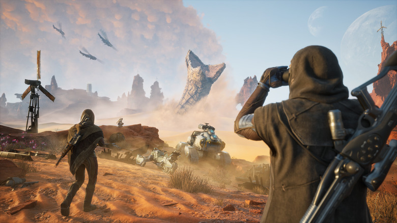 This is a screenshot from the upcoming game, Dune: Awakening. A hero (foreground) holds binoculars to watch a giant sandworm in the distance.