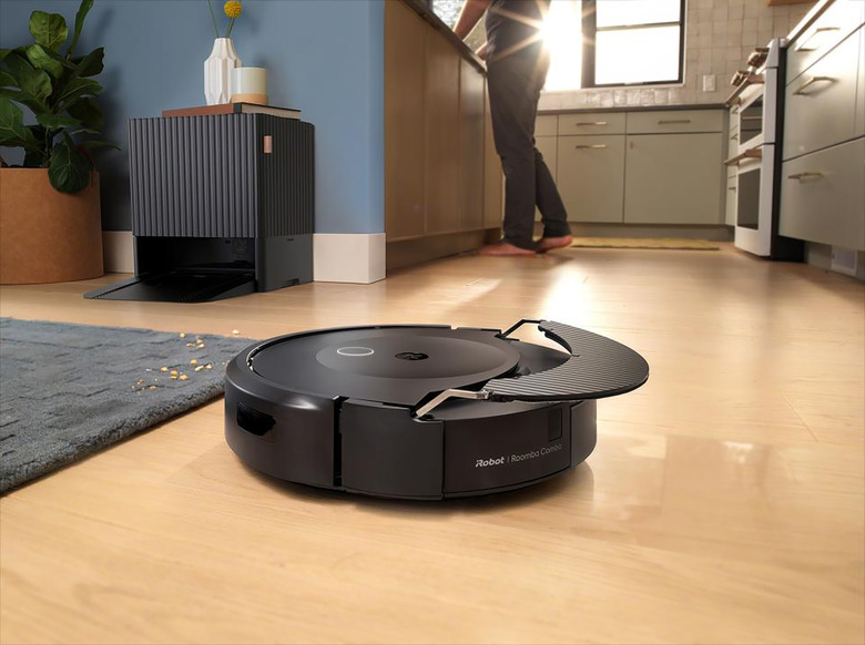 A robot vacuum near a kitchen with its dock in the background.