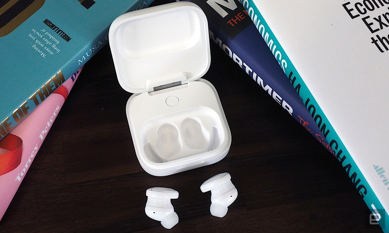 Image of the white Fairbuds on a brown wood table.