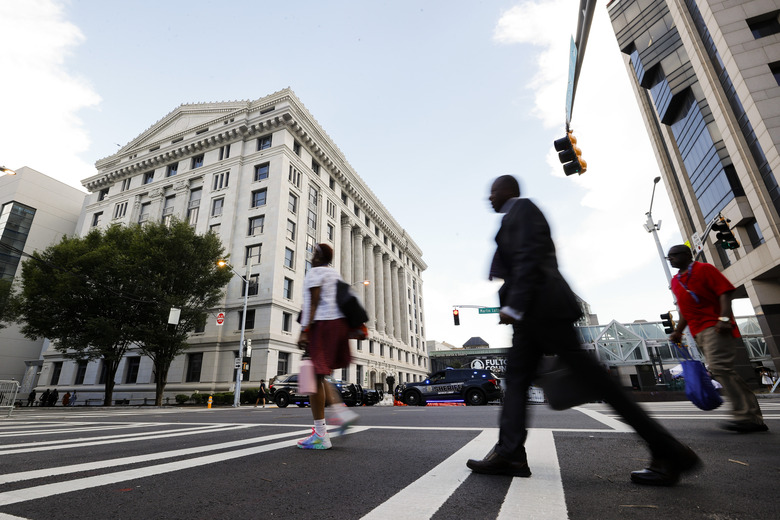FILE - People cross the street near the Fulton County Courthouse, Aug. 14, 2023, in Atlanta. Court and other systems in Fulton County, Georgia's most populous county, were hacked over the weekend, resulting in interruptions to routine operations, officials said Monday, Jan. 29, 2024, adding that the racketeering case against former President Donald Trump is unaffected. (AP Photo/Alex Slitz, File)