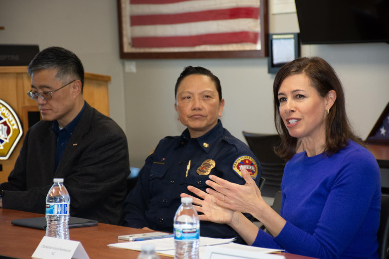A man in black, a cop and a woman wearing a blue top sitting together.
