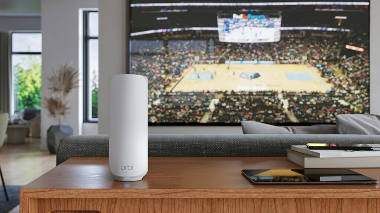 A Netgear Orbi 370 on a cabinet in front of a TV.