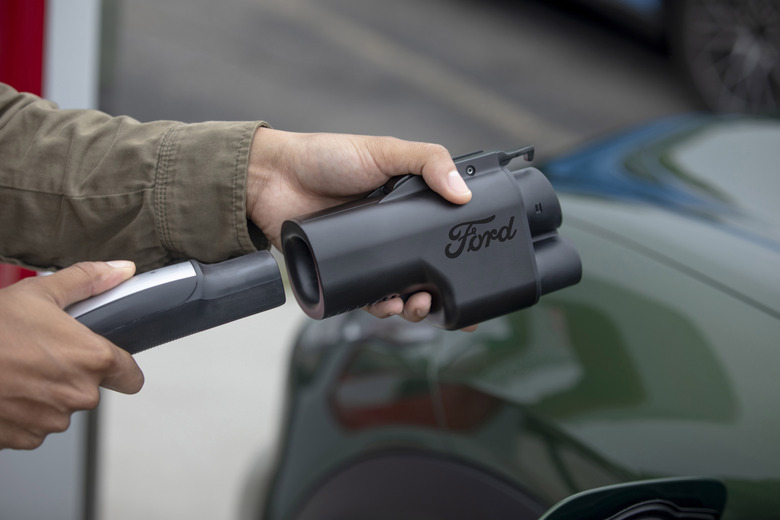 Hands holding a charging line and a Ford-branded charging adapter.