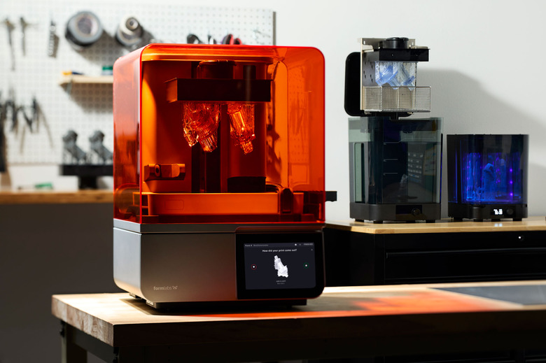 Image of the new Formlabs Form 4 3D printer on a workbench, with other Formlabs' accessories in the background and a pinboard with tools in the blur.