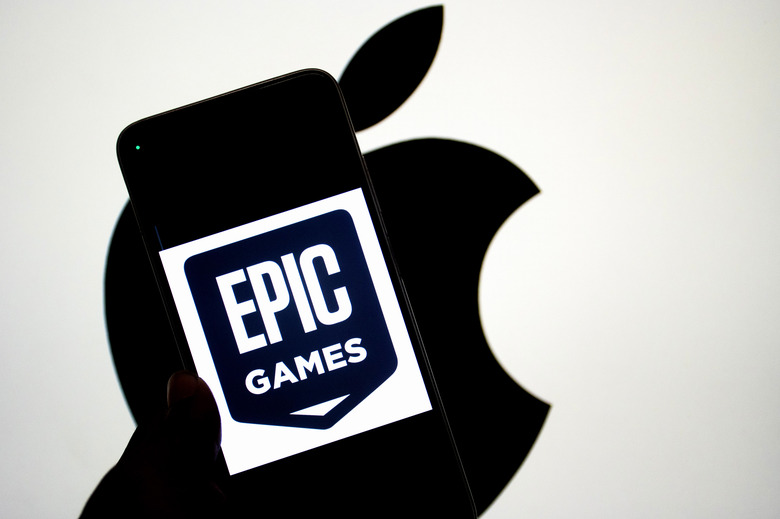INDIA - 2024/09/14: In this photo illustration, an Epic Games logo seen displayed on a smartphone with an Apple logo in the background. The relationship between Epic Games and Apple became widely known due to a legal dispute. In 2020, Epic Games, the creator of the popular game Fortnite, challenged Apple's App Store policies by introducing a direct payment option in Fortnite, bypassing Apple's 30% commission on in-app purchases. Apple responded by removing Fortnite from the App Store, leading to a major lawsuit. Epic accused Apple of anti-competitive behavior, claiming that the company had a monopoly on app distribution and payments within its ecosystem. The case, which addressed broader issues of app store policies and digital marketplaces, attracted significant attention and sparked debate about the control tech giants have over their platforms. (Photo Illustration by Avishek Das/SOPA Images/LightRocket via Getty Images)
