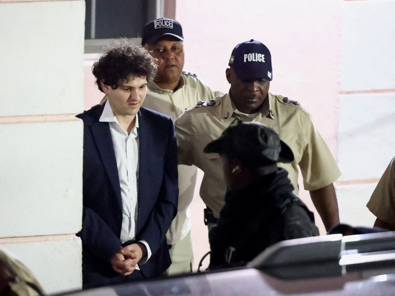 Sam Bankman-Fried, who founded and led FTX until a liquidity crunch forced the cryptocurrency exchange to declare bankruptcy, is escorted out of the Magistrate Court building after his arrest, in Nassau, Bahamas December 13, 2022. REUTERS/Dante Carrer