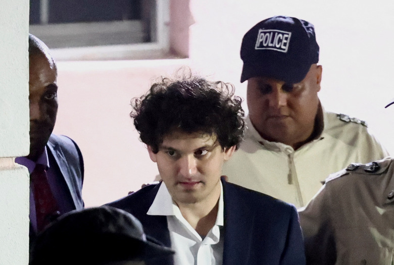 Sam Bankman-Fried, who founded and led FTX until a liquidity crunch forced the cryptocurrency exchange to declare bankruptcy, is escorted out of the Magistrate Court building after his arrest in Nassau, Bahamas December 13, 2022.  REUTERS/Dante Carrer