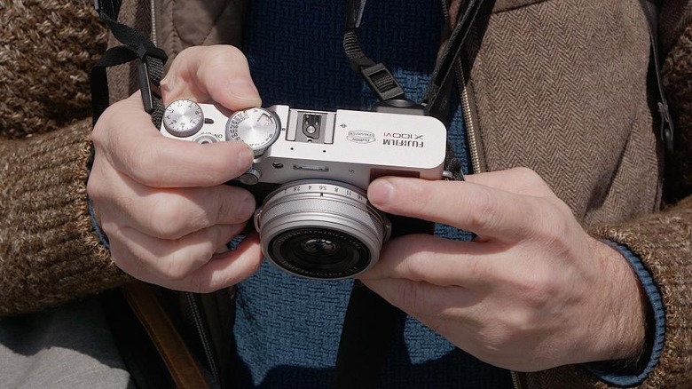 Two hands holding the Fujifilm X100 VI camera.