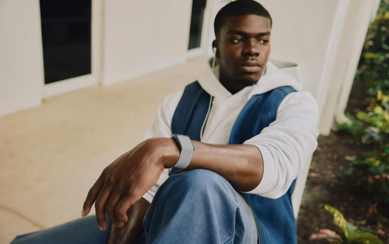 A person wearing a gray Whoop band and listening to music on a pair of wired headphones.